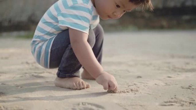 一个小男孩 (12-23个月) 在沙滩上玩耍