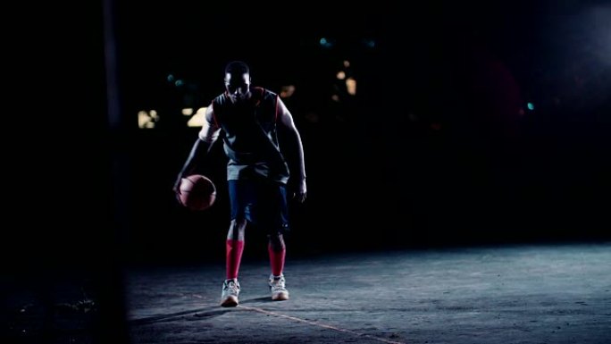 篮球运动员晚上在球场上弹跳球