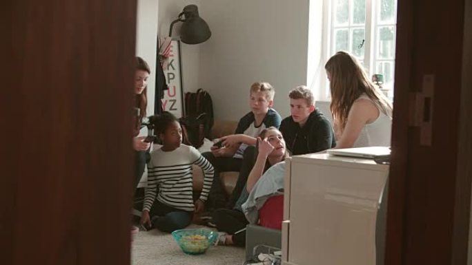 一群青少年在卧室玩电子游戏和聊天