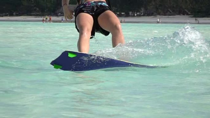慢动作特写: 年轻的风筝冲浪女人在完美的蓝色泻湖里风筝冲浪