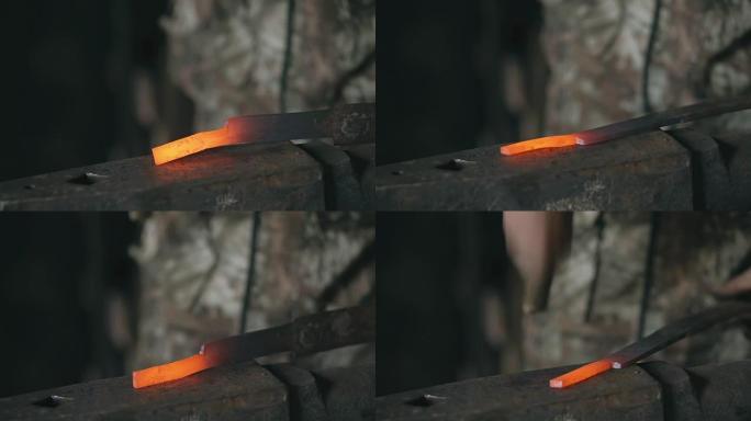大胡子的年轻人铁匠的特写镜头用火花烟花在铁匠铺的铁砧上手工锻造铁水