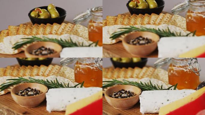 一碗绿橄榄，香料，脆皮饼干，果酱，迷迭香药草，奶酪和核桃