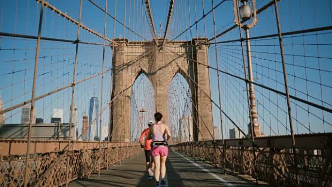 在炎热的夏日，两名成年妇女沿着纽约布鲁克林大桥奔跑。不同年龄的人过着健康的生活方式4K