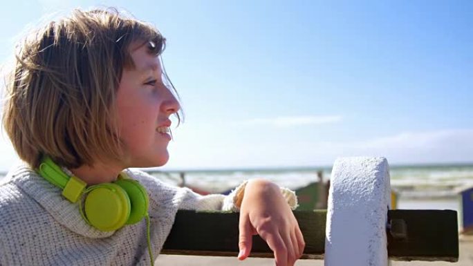 戴着耳机的少女看着海滩4k