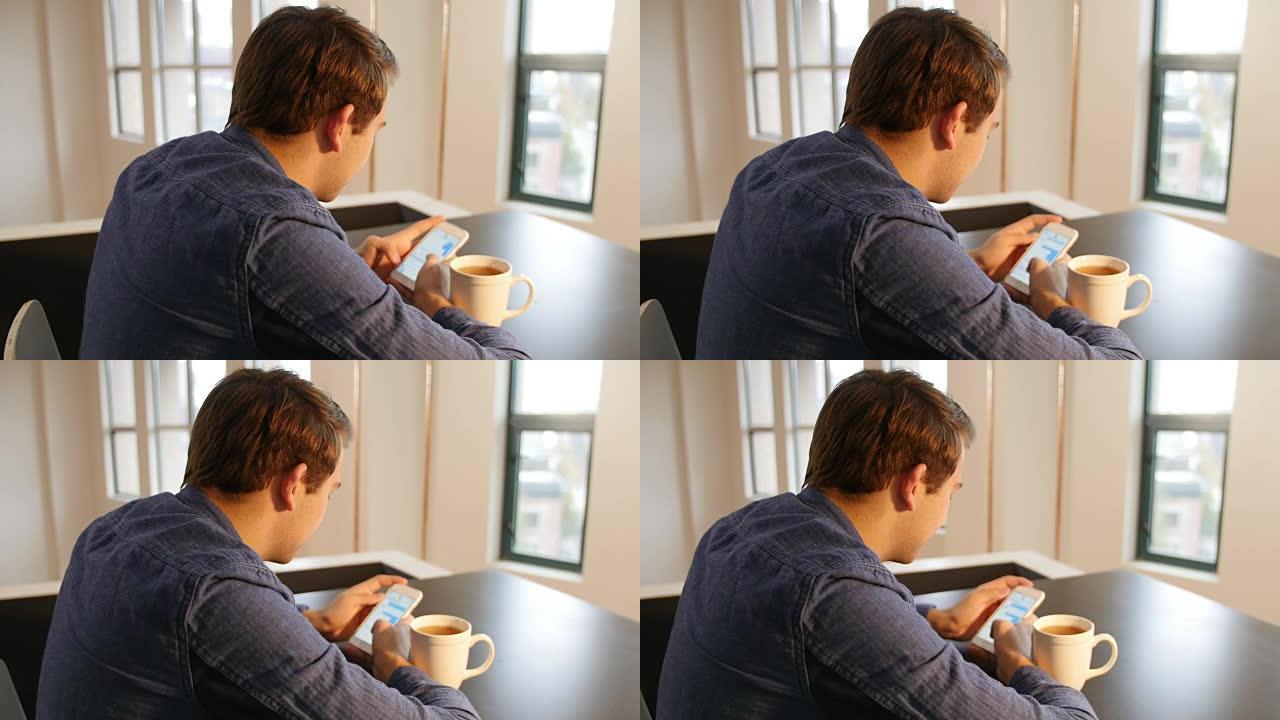 男人用手机在桌子上放黑咖啡