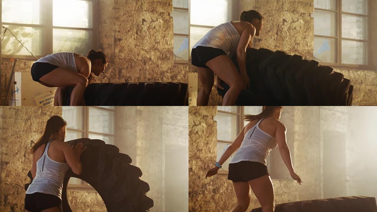 健康的女运动员举重/翻转轮胎的努力作为她的交叉健身/健美训练的一部分。她在废弃建筑改建的健身房锻炼。