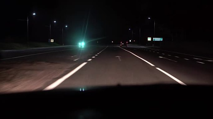 从车内可以看到夜景。前灯和其他汽车在乡村道路上运动