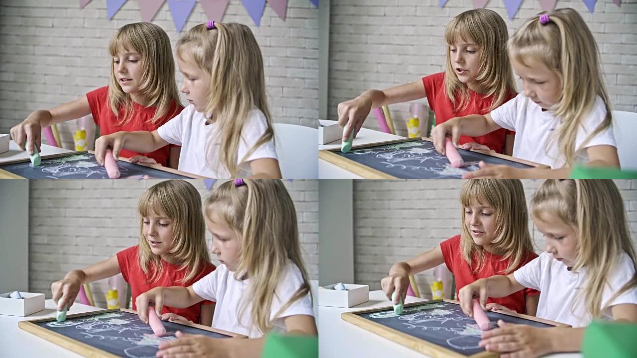 可爱的女孩在黑板上用粉笔画画