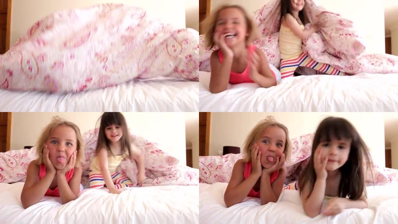 两个女孩躲在床上的羽绒被下