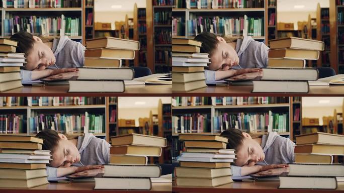 年轻漂亮的高加索女学生睡在桌子上，周围是成堆的书和论文，电话在她面前撒谎，她在大大学图书馆里