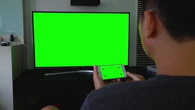 使用智能手机和电视的肩拍，绿屏