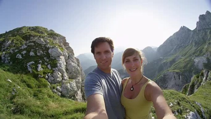 自拍镜头闪耀快乐的年轻夫妇在夏天的山顶上自拍