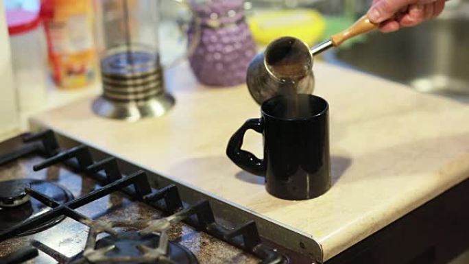 在咖啡壶中煮沸的咖啡。一个男人的手拿着锅，把咖啡倒在杯子里