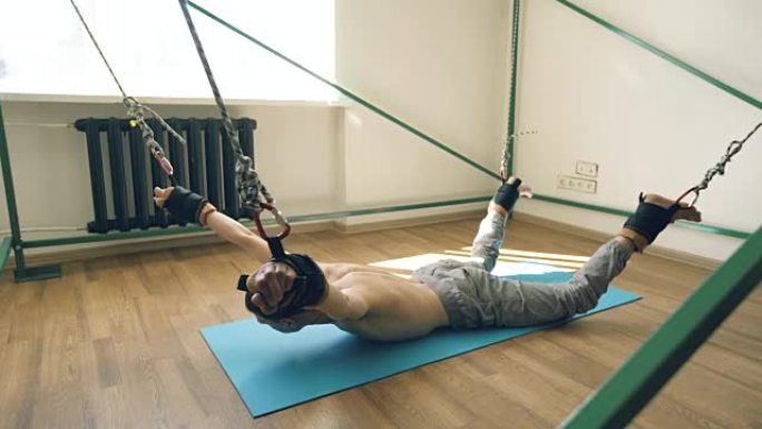 年轻人在训练瑜伽设备上放气，用绳子拉着胳膊和腿