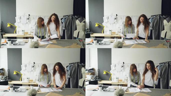 当她的同事带着草稿来找她，展示和改善形象并与同事讨论时，年轻女性服装设计师正在画草图。