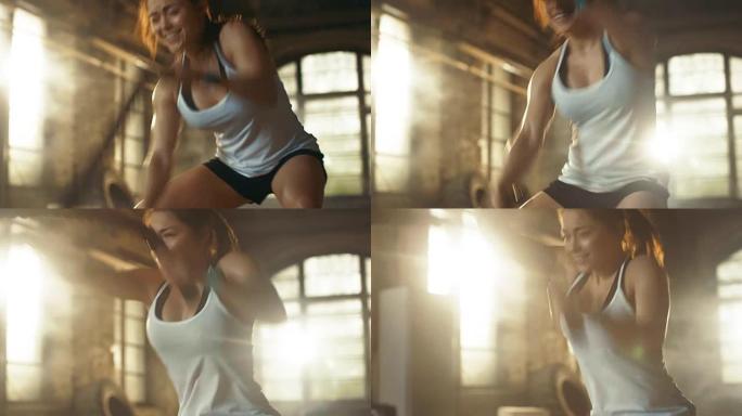 运动女孩在健身锻炼/高强度间歇训练期间积极在健身房用战斗绳锻炼。她肌肉发达，满头大汗，健身房在荒芜的