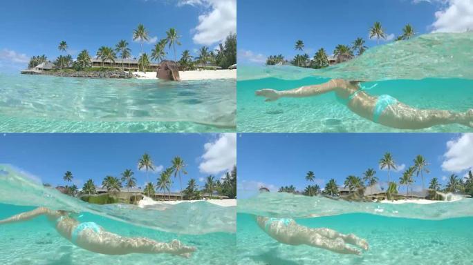 慢动作: 开朗的女人游过令人惊叹的库克群岛的海滨酒店