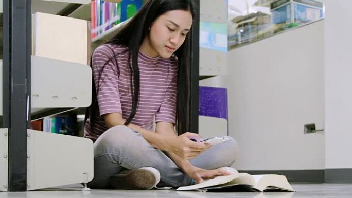 妇女坐在图书馆看书。女大学生坐在图书馆的地板上。