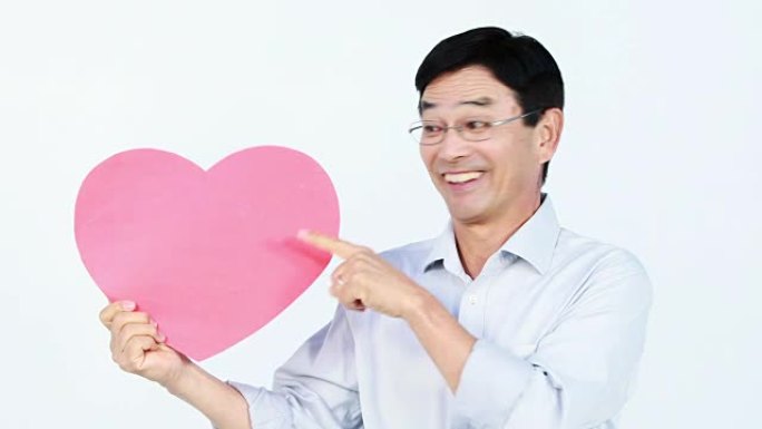 微笑的亚洲男子抱着一颗粉红色的心
