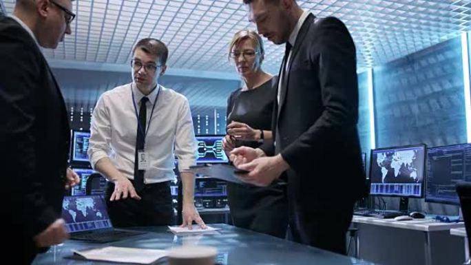 政府特工团队借助触摸屏交互式桌子在充满动画屏幕的计算机的最先进监控室中跟踪逃犯。