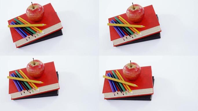苹果和彩色铅笔在书堆上