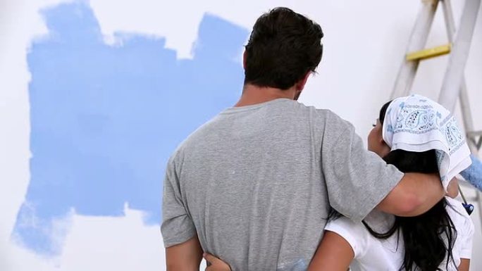 年轻夫妇看着粉刷的墙壁