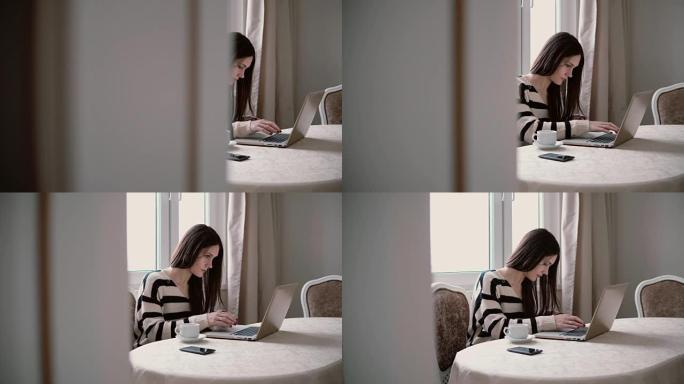 女人使用笔记本电脑，在明亮的用餐中享受早晨的咖啡。向右滑动，通过打开的门查看