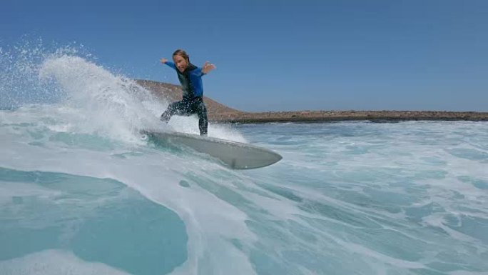 低角度视角: 酷男冲浪者在他有趣的冲浪板上快速急转弯。