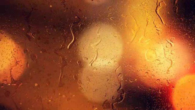 雨滴在行驶中的汽车的bokeh背景下从玻璃上流下
