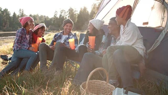 露营旅行中的多代家庭坐在帐篷外面