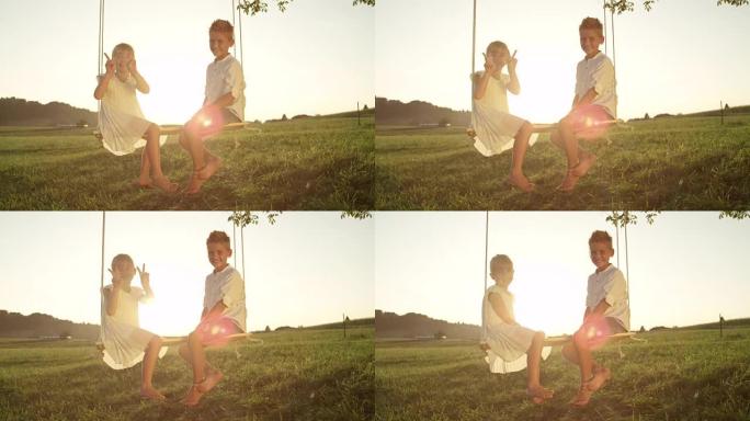 慢动作快乐的小男孩和女孩坐在日落时摆姿势拍照