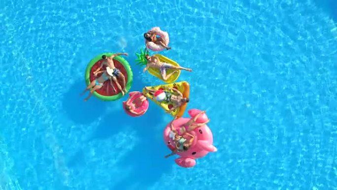 空中: 欢快的人在游泳池中有趣的充气漂浮物上玩球