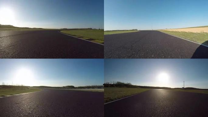 FPV低角度: 赛车在阳光明媚的日子在赛道上快速行驶