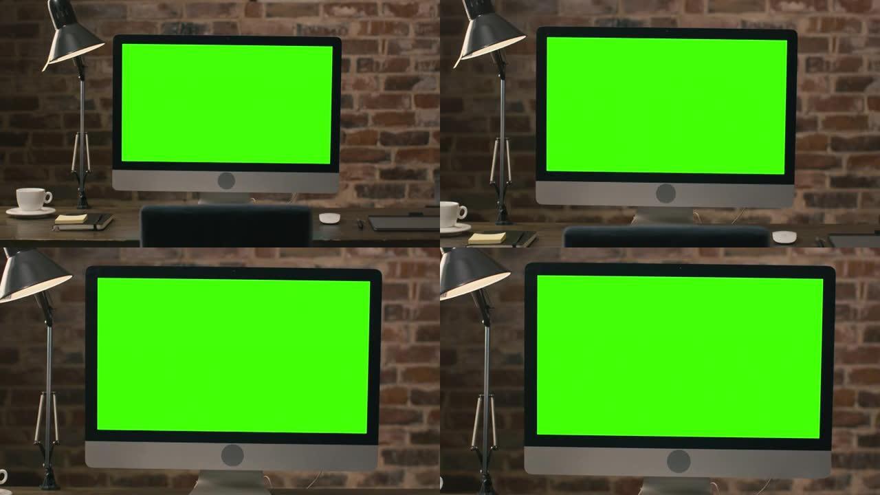 电脑显示器的镜头，绿屏站在阁楼上的平板电脑、灯、咖啡杯、笔记本和鼠标旁边。