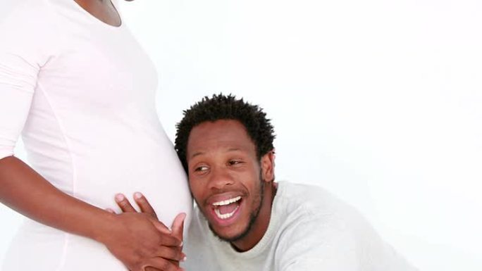 微笑的丈夫听着怀孕的妻子肚子