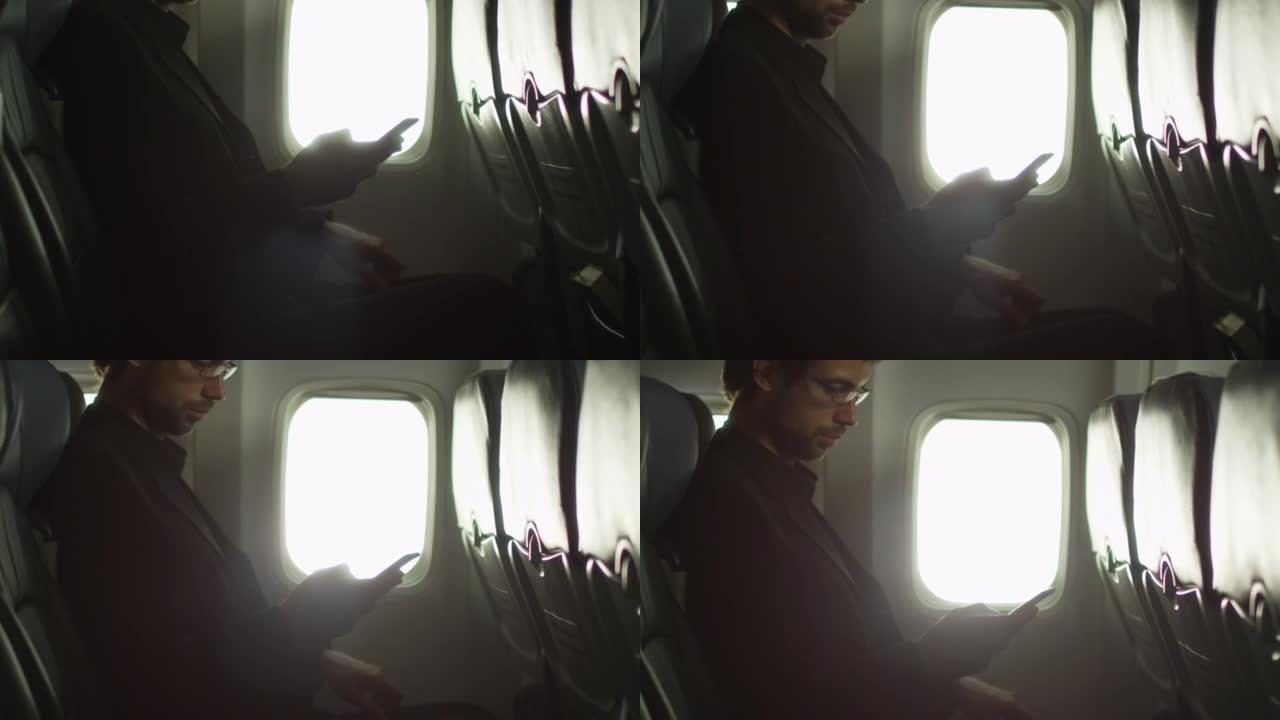 年轻人正在窗户旁边的飞机内使用智能手机。