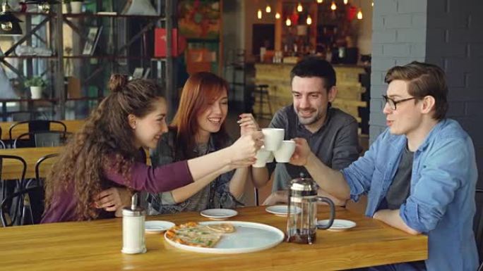 友好的团队正在用饮料和比萨饼庆祝咖啡馆项目的成功结束，他们在聊天和叮当喝茶。外出就餐和友谊概念。