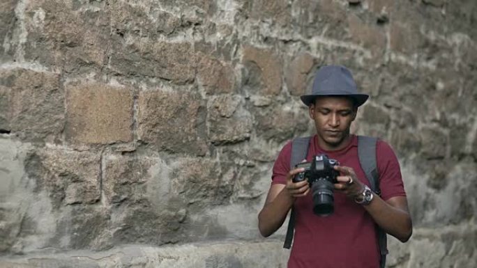 混血快乐的旅游男子站在欧洲著名建筑附近的dslr相机上拍照