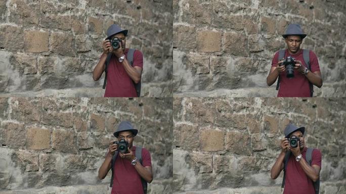 混血快乐的旅游男子站在欧洲著名建筑附近的dslr相机上拍照