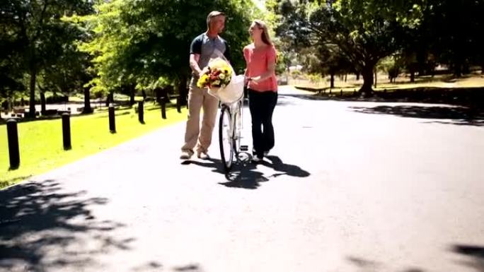 幸福的夫妇骑着自行车和一束鲜花散步