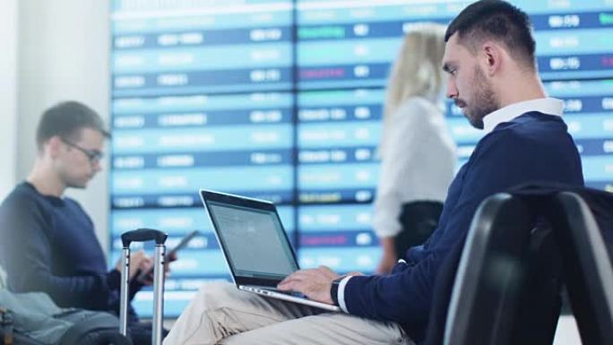 男子在机场候机室等候登机时在笔记本电脑上工作。