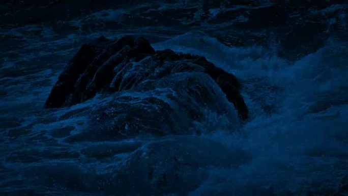 晚上，大浪冲过海洋中的岩石