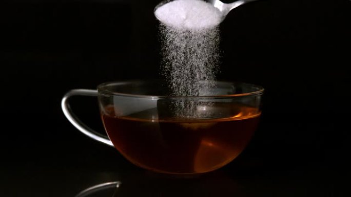 茶匙将糖倒入一杯茶中