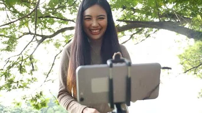 海: 使用手机，年轻女子用智能手机给公园里的朋友视频通话