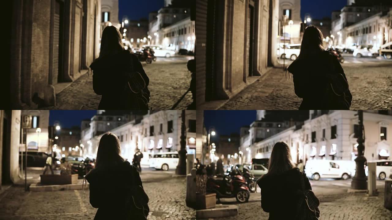 深夜，年轻时尚女子穿过荒芜的小巷走到城市大街的后景