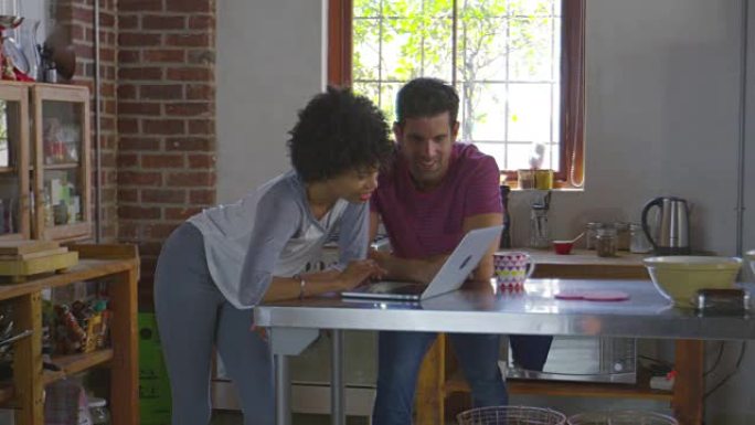 年轻的混血夫妇在厨房里使用计算机，在R3D上拍摄