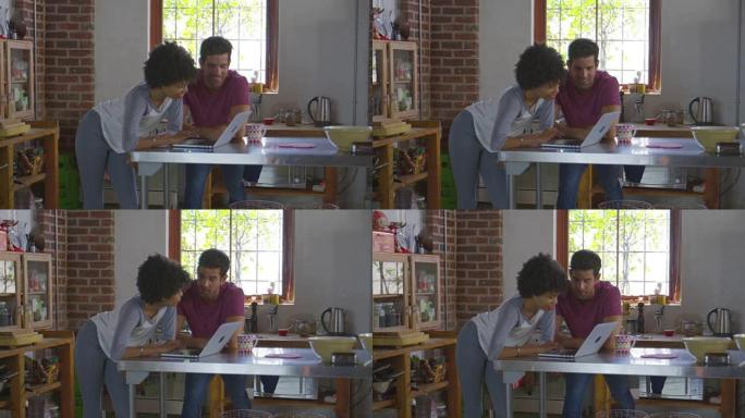 年轻的混血夫妇在厨房里使用计算机，在R3D上拍摄