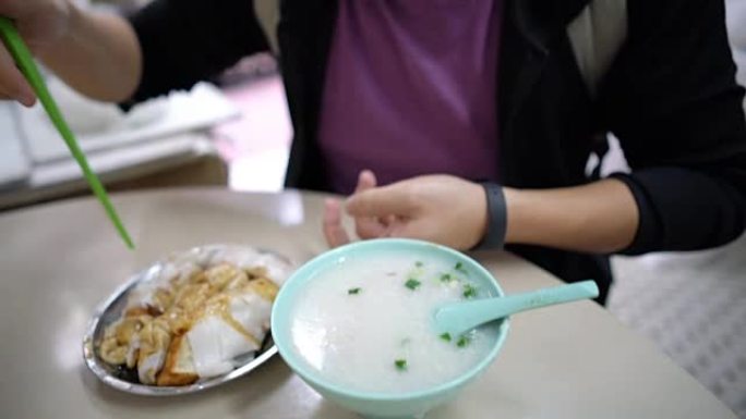 亚洲游客在香港本地餐厅吃米粉卷和粥。