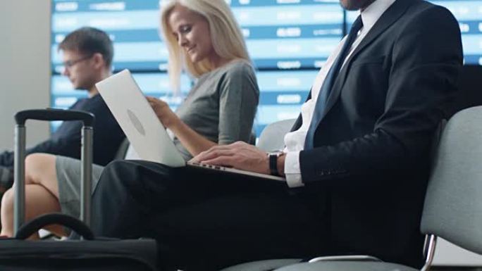 商人在机场候机室等候登机时在笔记本电脑上工作。