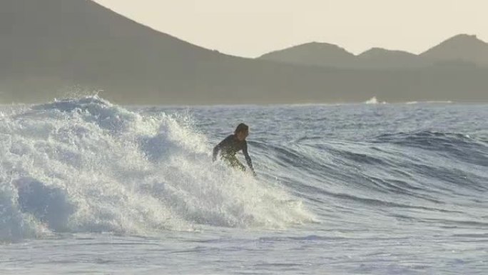 慢动作: 冲浪板上的凉爽游客雕刻危险的深蓝色破浪